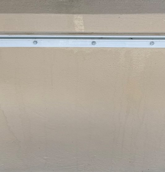 Wall beneath the window — bug residue, webbing, and dirt spatter washed off the wall and sill. after
